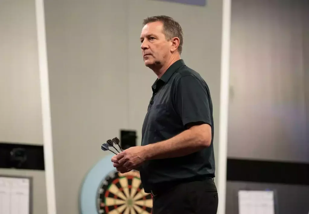 Männlicher Darts-Profi während eines PDC-Major-Turniers mit fokussierter Wurfhaltung